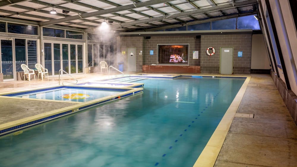 A spacious indoor heated pool and spa complex with steam rising from the water.