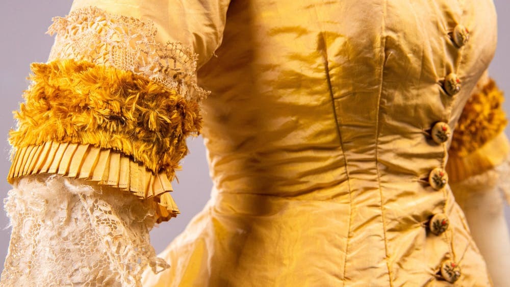 Close up of of bust on a gold 19th century  dress with white frills on sleeve