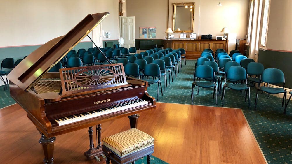 BMI Humffray Room - looking down the room with a grand piano in the foreground and chairs behind it.