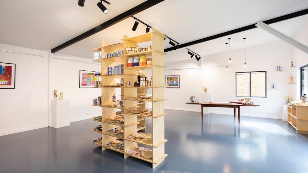 Inside view of the gallery with large shelf in the middle with pots on it.