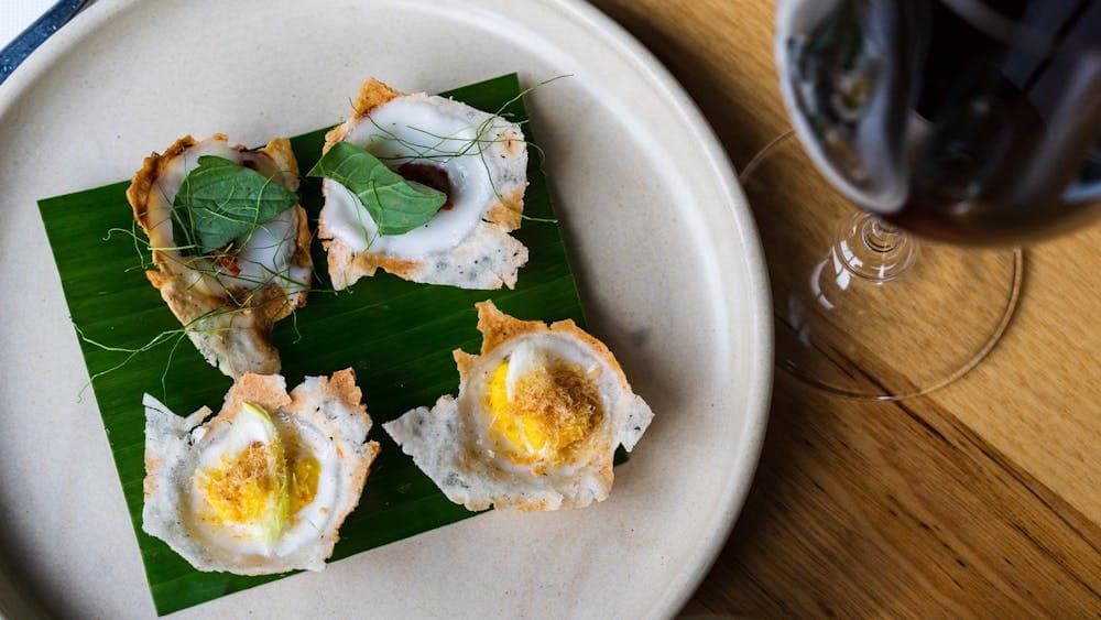 Overhead view of plate of Thai Cupcakes (Kanom Krok) with a glass of red wine