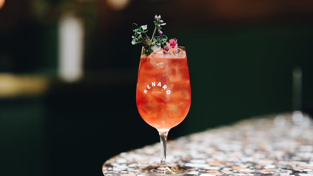 A spritz cocktail sitting on a bar table