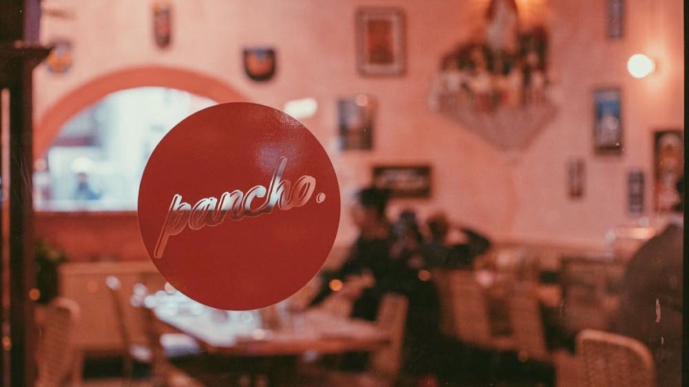 Window with round red pancho decal with restaurant tables behind