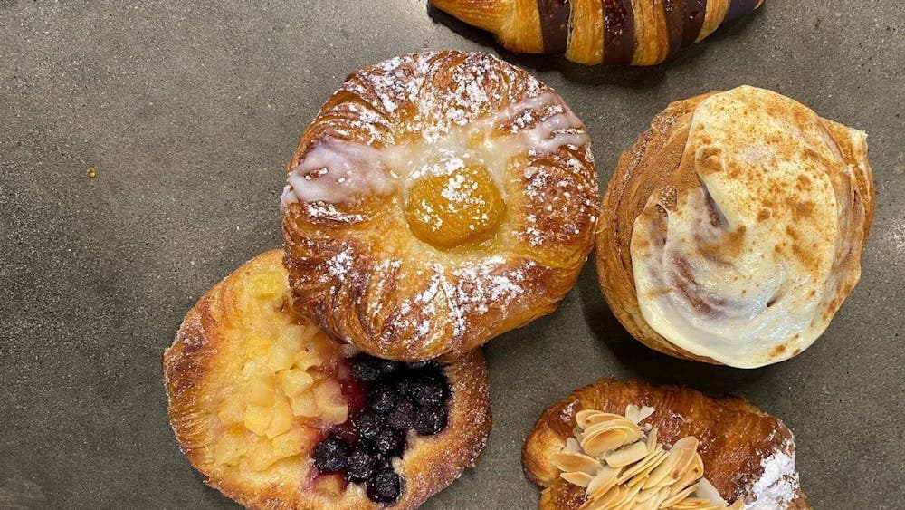 Aerial shot of five pastries, tarts and croissants on flat surface