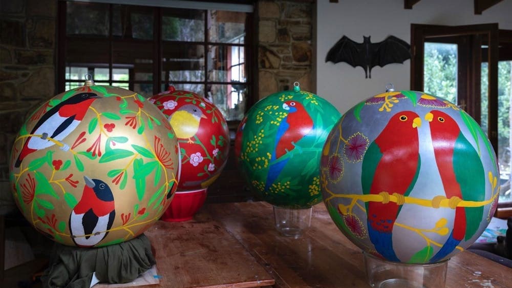 4 bright coloured baubles with native birds sit on a table, drying on bowls