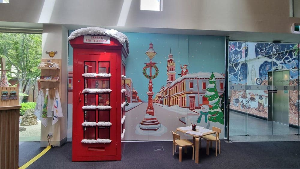 Santa's Red Telephone Box sits in front of a cartoon mural of Lydiard Street