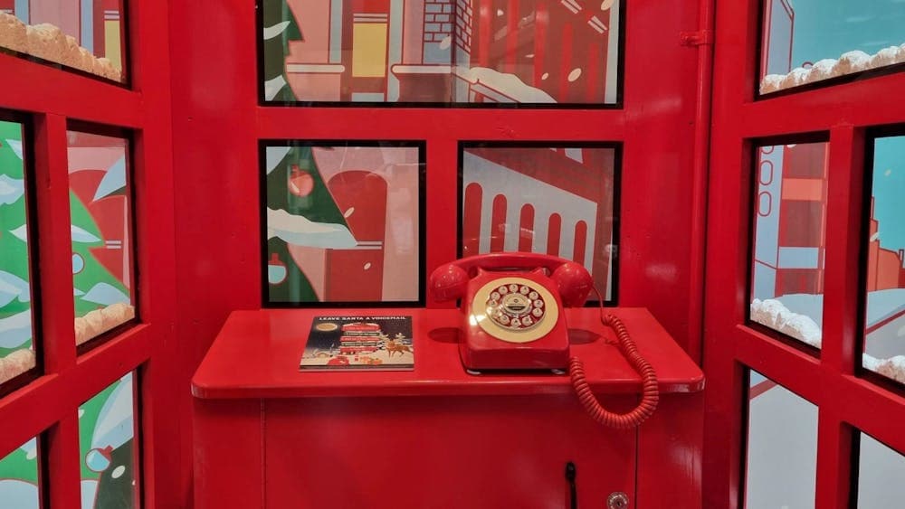 A red rotary phone sits inside the red telephone box