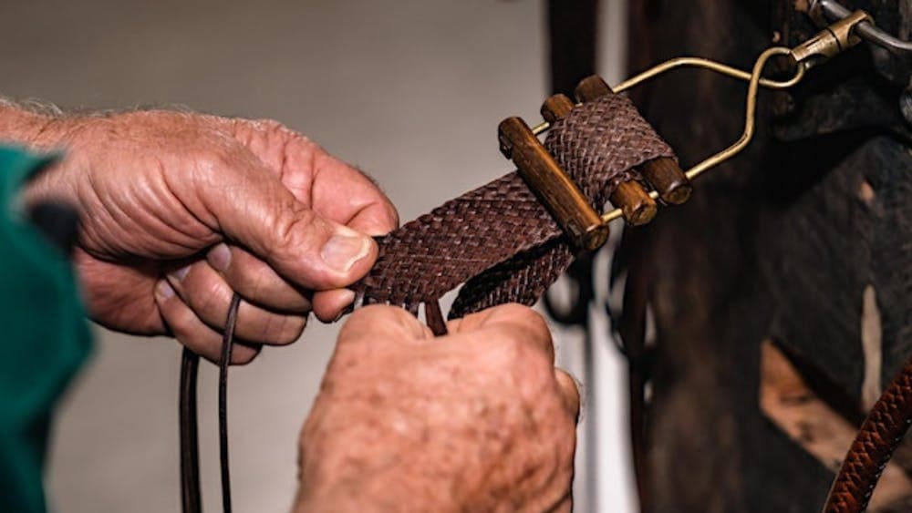 Close up of hands plaiting leather for a belt