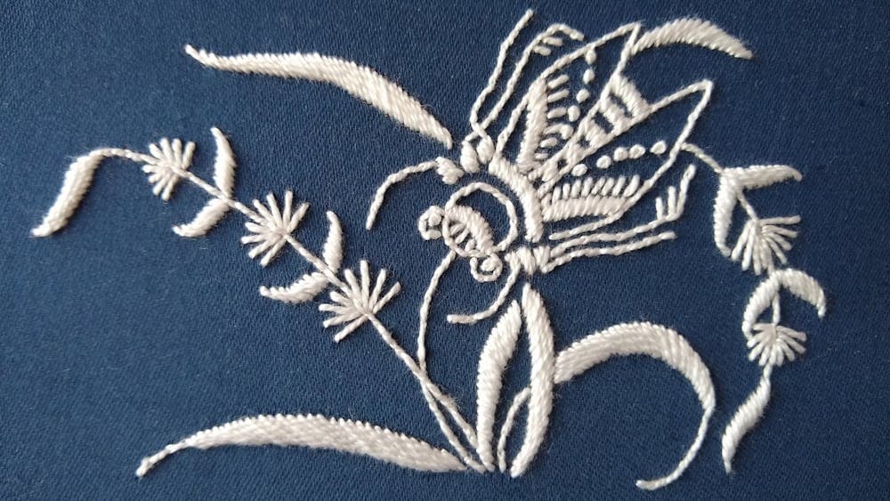 White floral embroidery on blue fabric