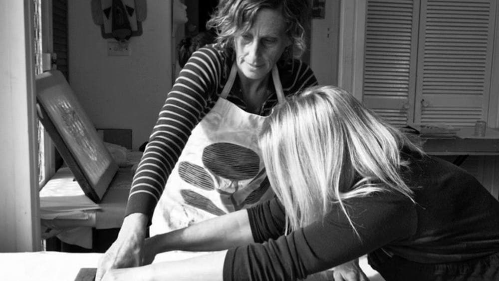 Black and white image of two women screenprinting