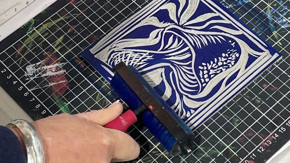 Close up of hand lino printing a blue and white design