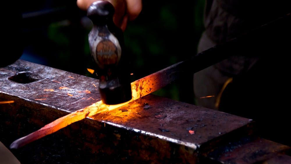 Hammer hitting hot metal on anvil