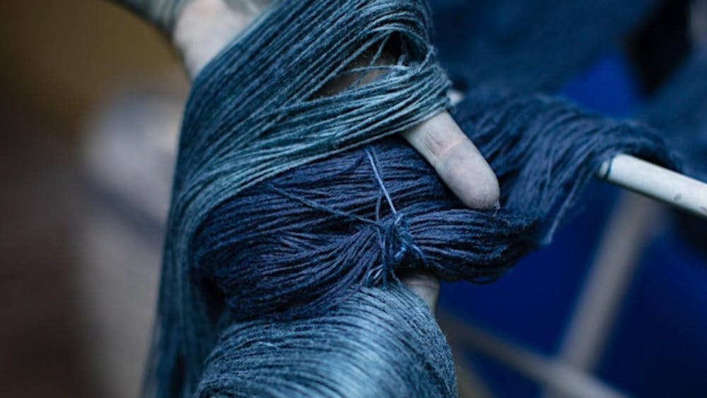 Indigo dyed yarn held in a pair of stained hands