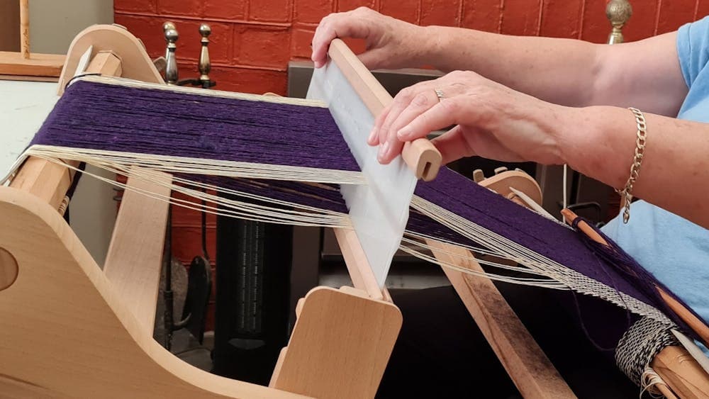 Hands working yarn on a loom