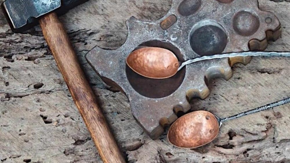 Copper serving utensils resting on bench with hammer