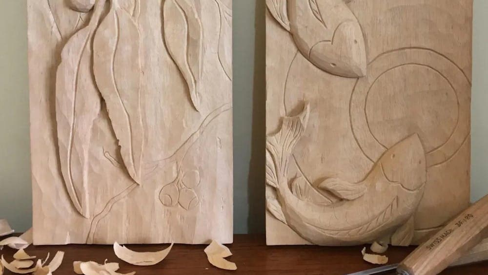 Two hand carved wood panels. One with gum leaf design, the other with koi fish