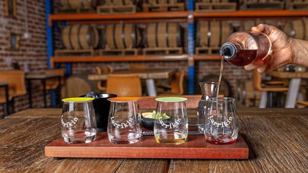 Gin being poured into small glass on tasting board