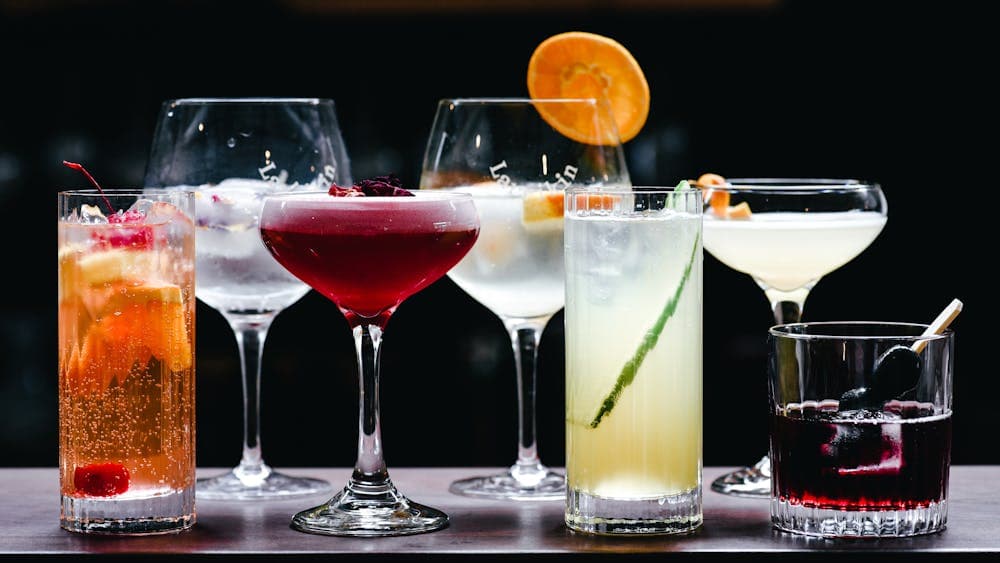 7 cocktails lined up on a bar top