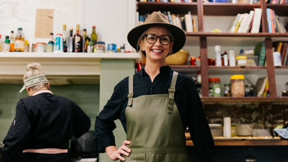 Cat Clarke standing in front of a book shelf smiling