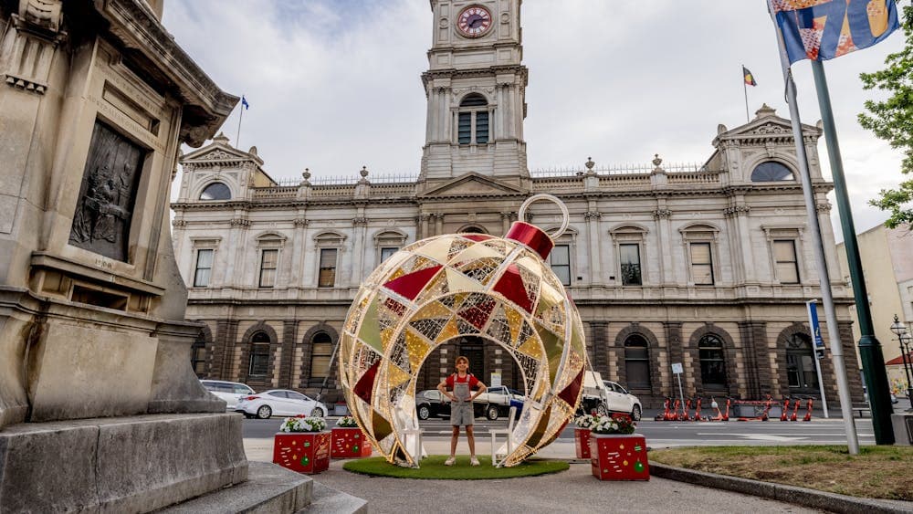 The giant Christmas Bauble sits in front of Town Hall with a little girl in red standing inside it