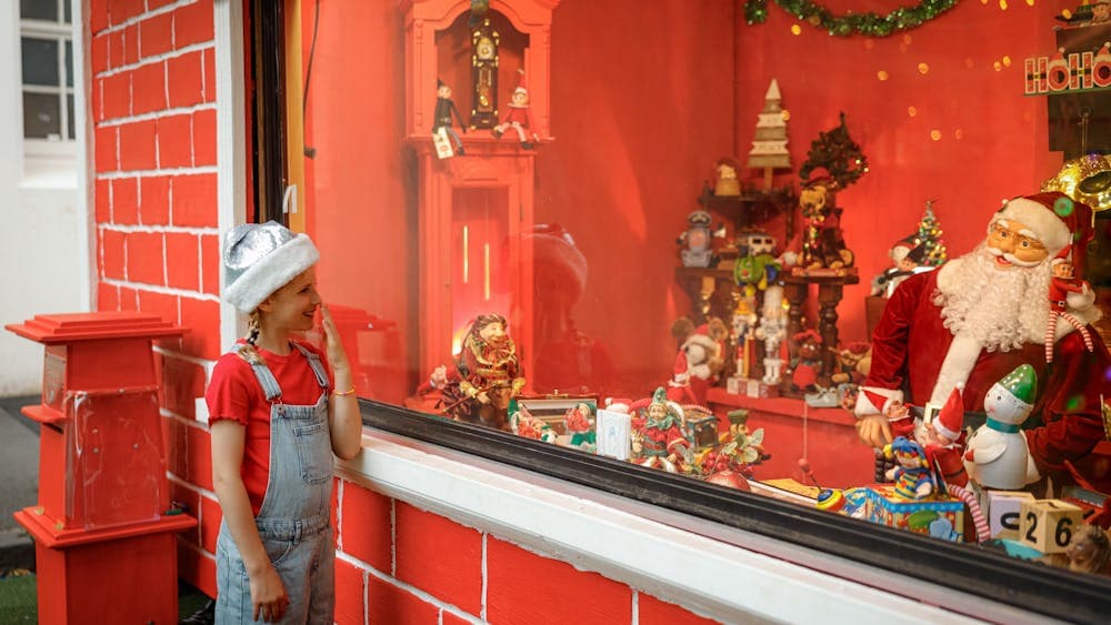 A girl in red stands and looks into the Magical Christmas Emporium