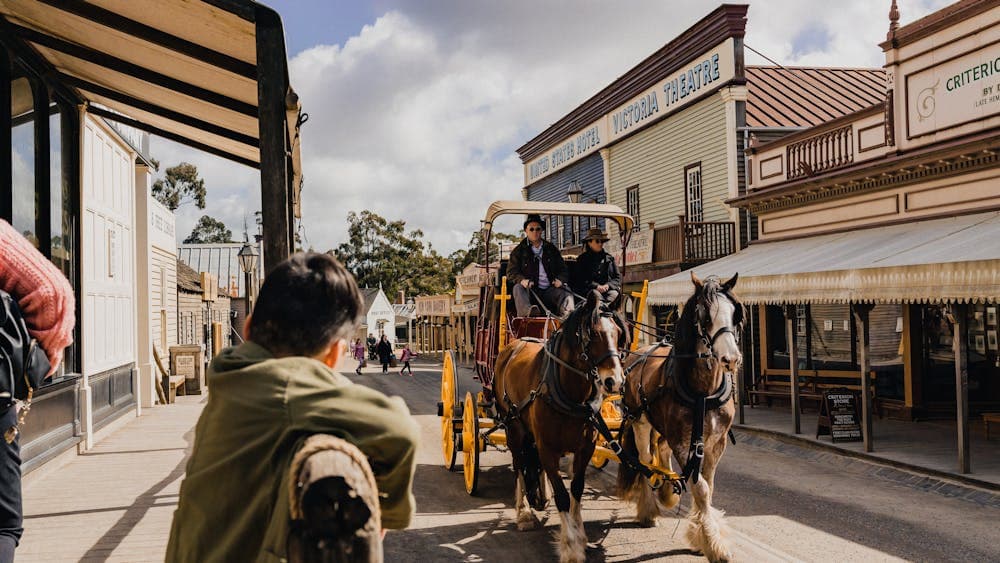 Horse carriage on Sovereign Hill's Main Street with young boy looking on