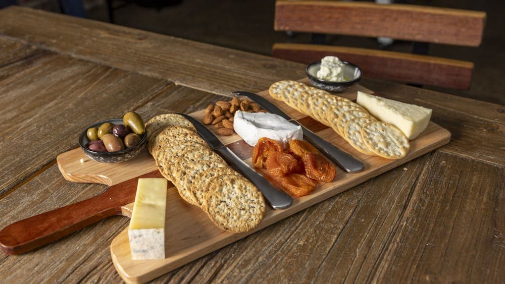 a wooden board with cheeses, dried fruits and crackers