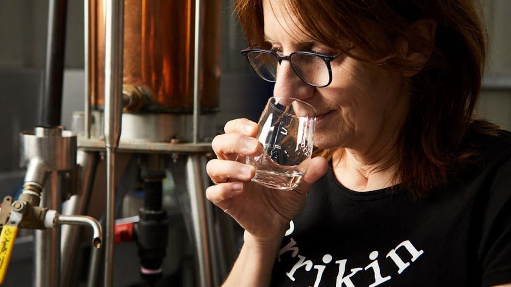 A lady smelling a small sample of a distilled spirit