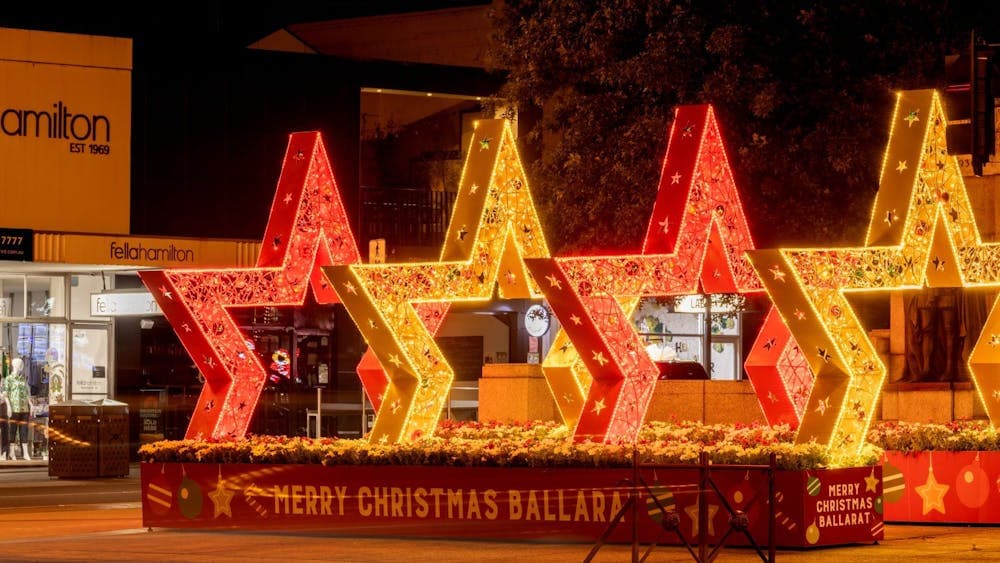 2 red and 2 gold stars create an archway, and are lit up with Christmas lights