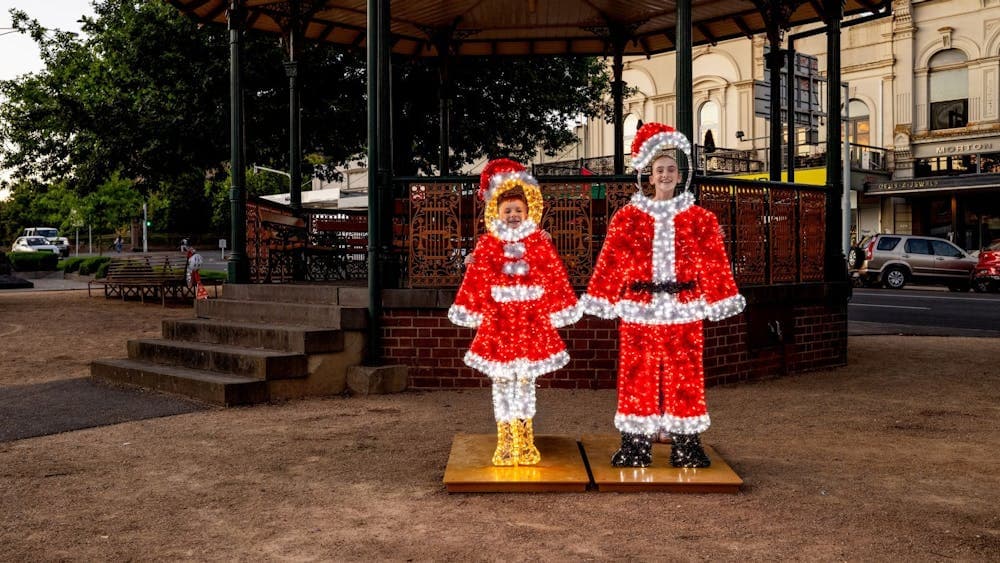 Two children put their faces into the holes to become Santa and Mrs Clause