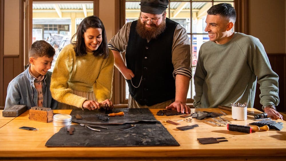 Family making keyring with a costumed leathermaker guiding them