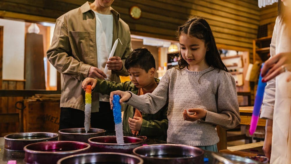 Two children dipping candles in cylinders