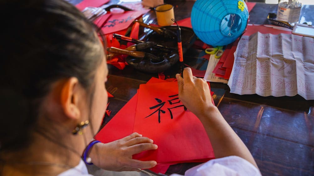 Child handwriting Chinese calligraphy on red paper