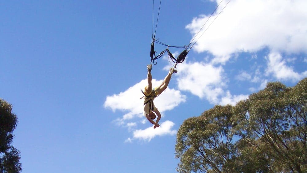 A person swings upside down on a giant swing harness