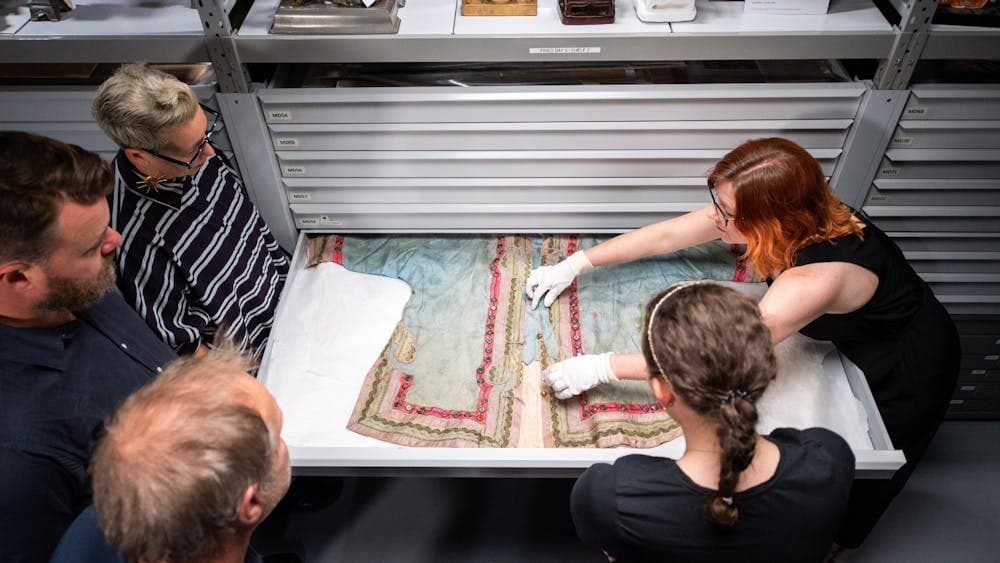 Curator showing Chinese garment in drawer to tour group