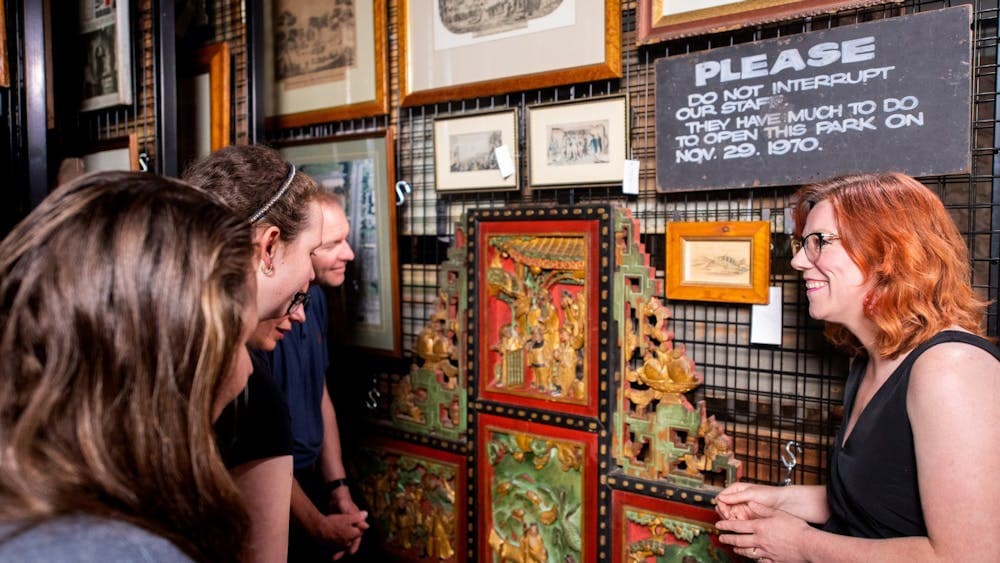 Curator showing historical Chinese temple panel to tour group