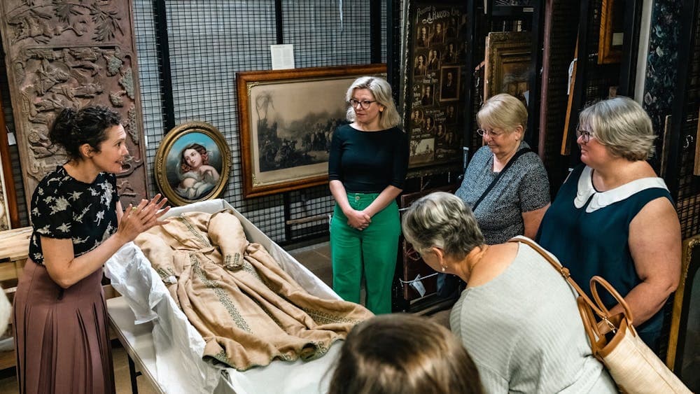 Curator showing historical dress stored in box to tour group