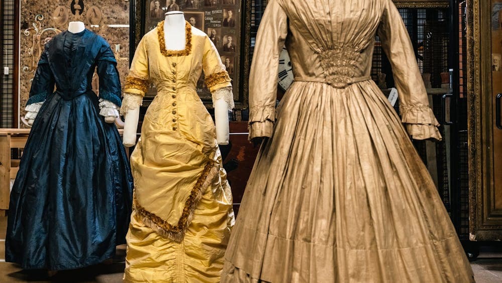 Three historical dresses (blue, gold and light brown) mounted on mannequins