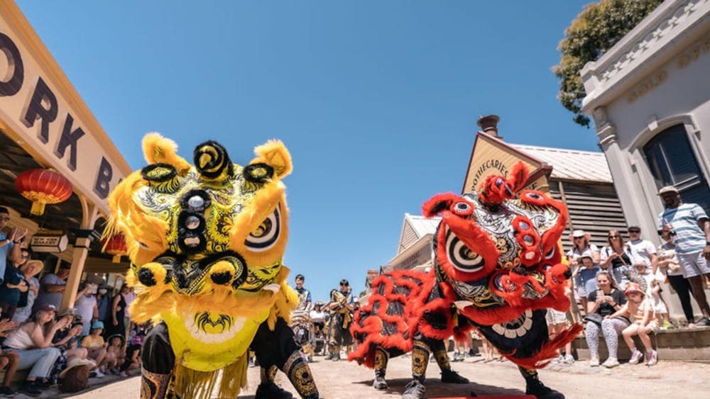 Two Chinese processional lions dancing on Main Street with a crowd of onlookers