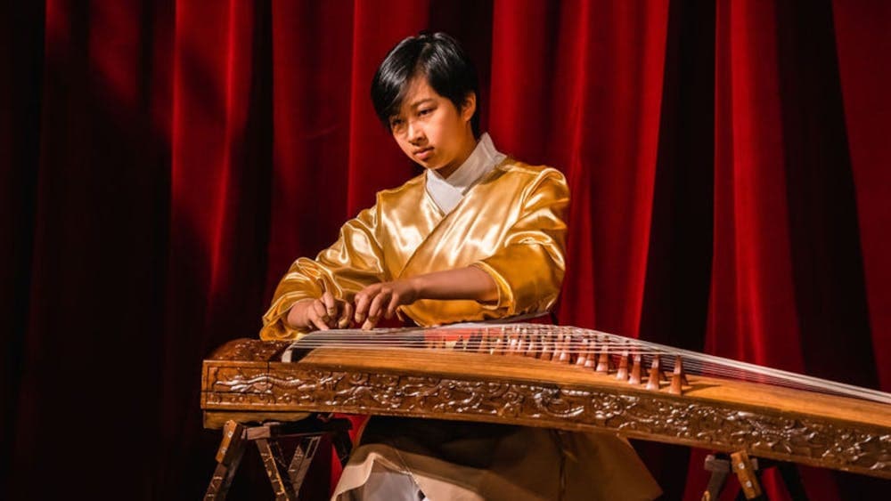 Performer playing traditional Chinese instrument on Victoria Theatre stage