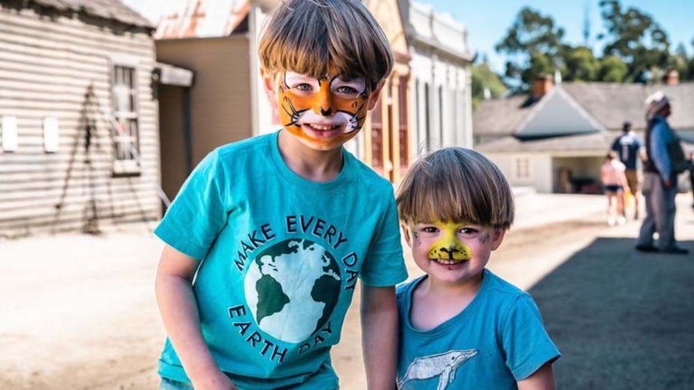 Two young boys wearing tiger face paint, standing on Main Street