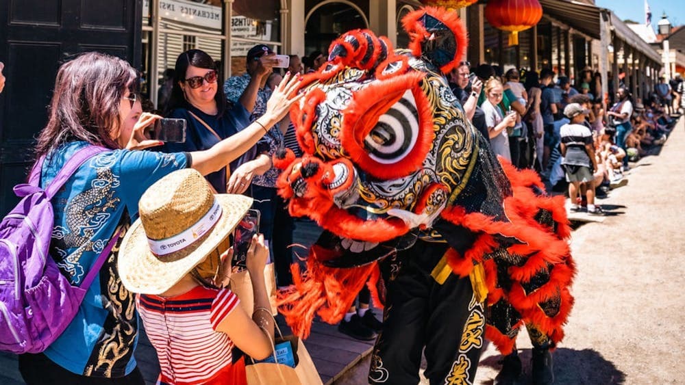 Visitors petting a Chinese processional lion on the head