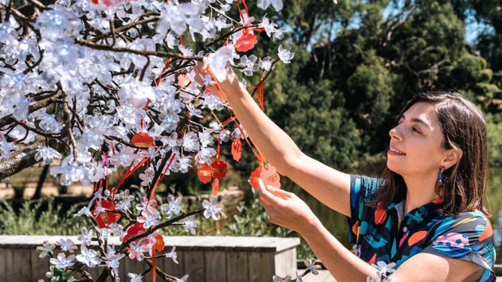 Woman placing Chinese wish card on a white tree