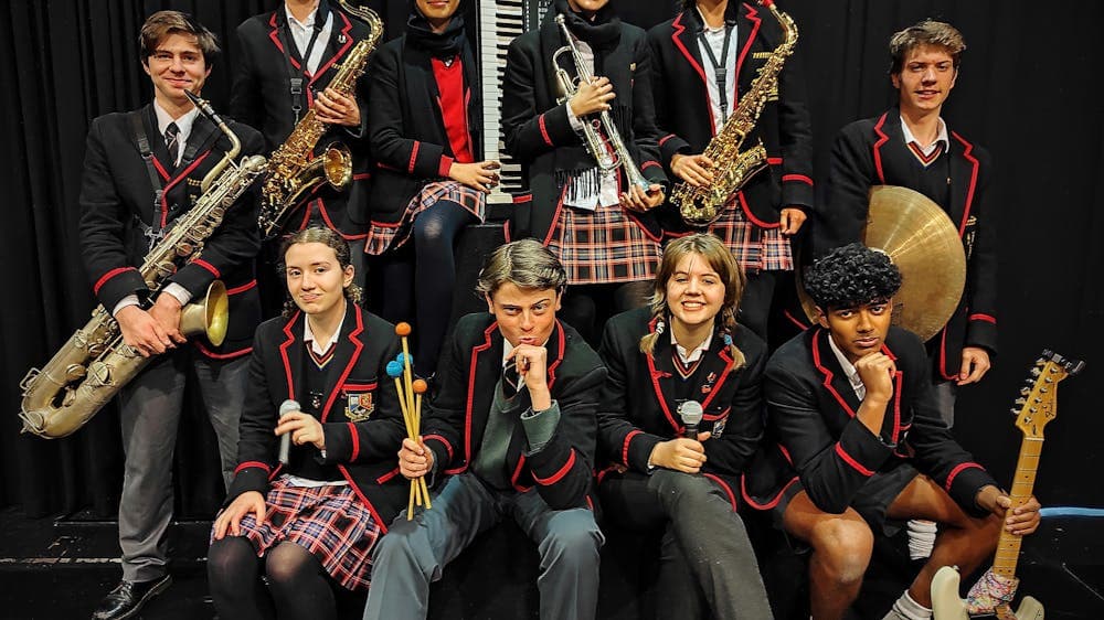 The Feet band sitting in two rows, smiling and holding their instruments