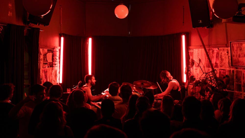 Sweet Nothing band sitting opposite each other, playing their instruments on stage