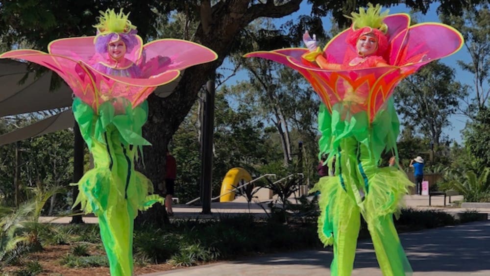 Two Stilt walkers dressed as Flowers walking through the gardens