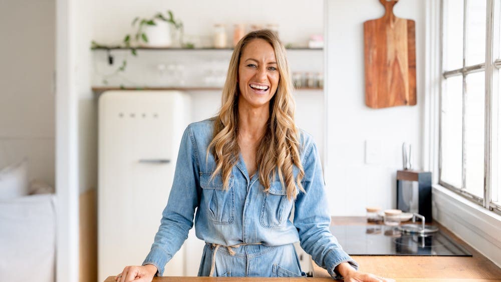 Mindy Woods stands, smiling behind a wooden bench.