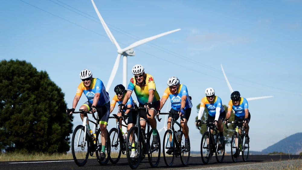 Road riders in the Spud 100 event in front of wind turbines