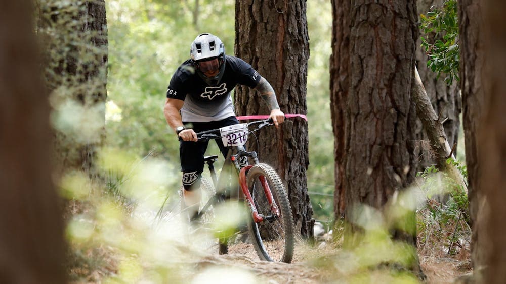 An enduro participant swerving around the tree lined path