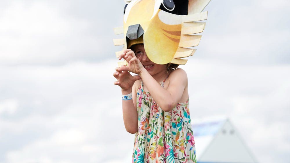 A little girl makes claws with her hands while wearing a dingo hat